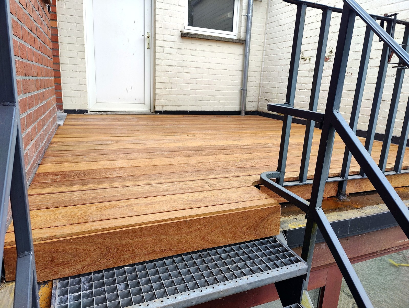 Professionele houten terrasafwerking met trappen en zwarte reling, op maat gerenoveerd in Oost-Vlaanderen door T Nieuw Project.