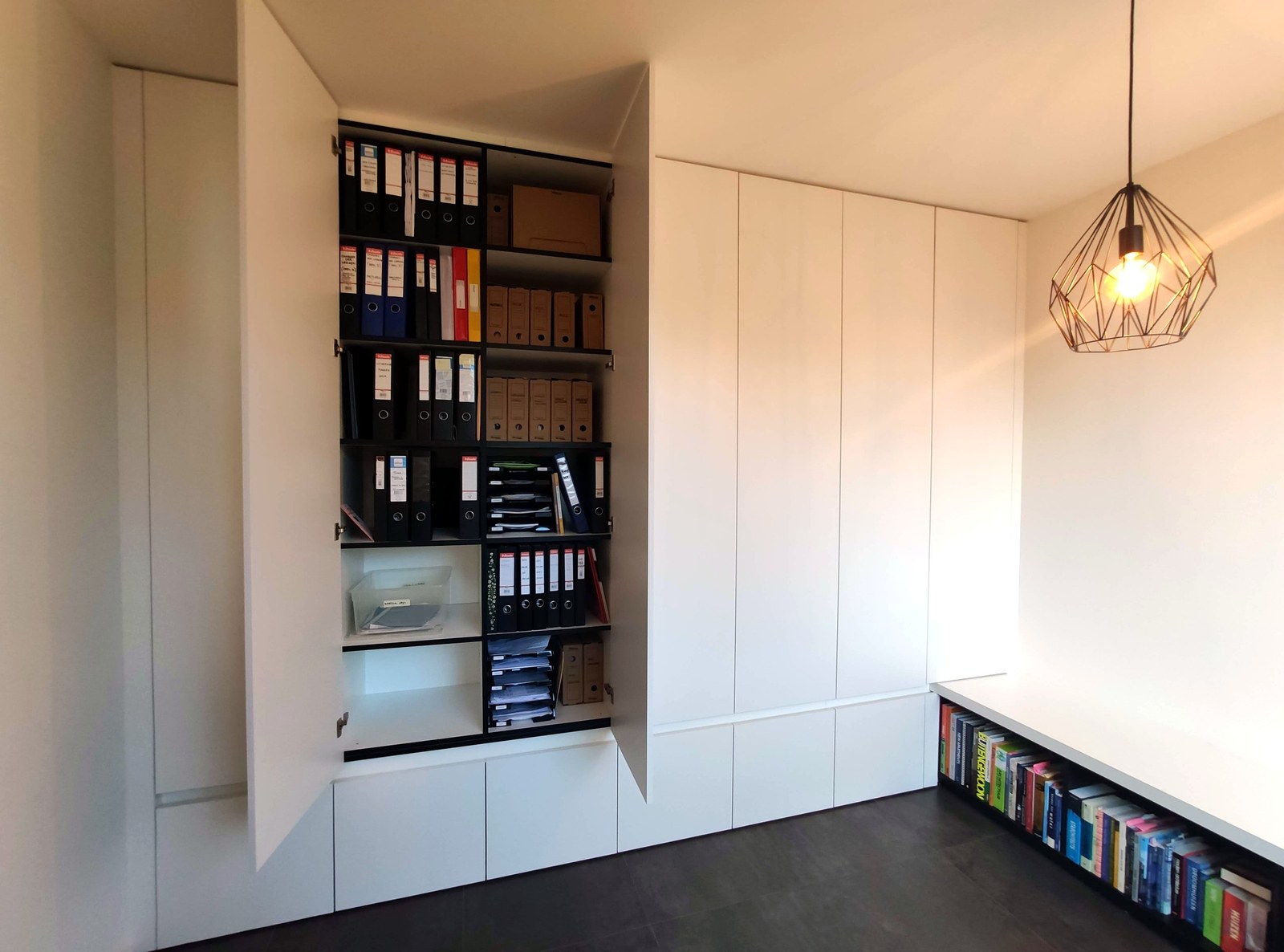 Moderne op maat gemaakte inbouwkast met wit panelwerk en zwarte planken, professionele renovatie in Oost-Vlaanderen door T Nieuw Project.