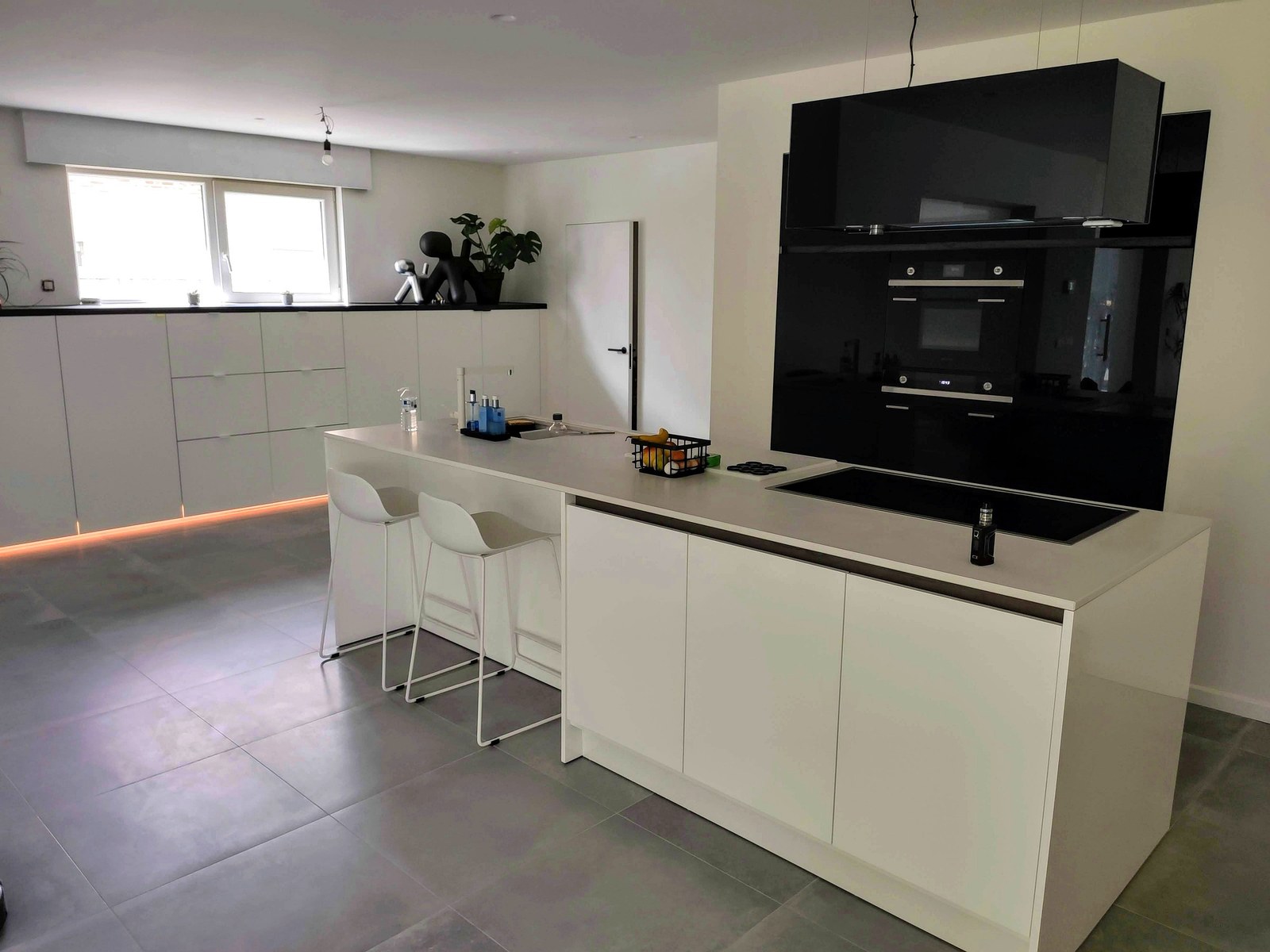 Moderne keuken op maat met witte kasten en zwart inbouwapparaat, professionele renovatie in Oost-Vlaanderen door T Nieuw Project.