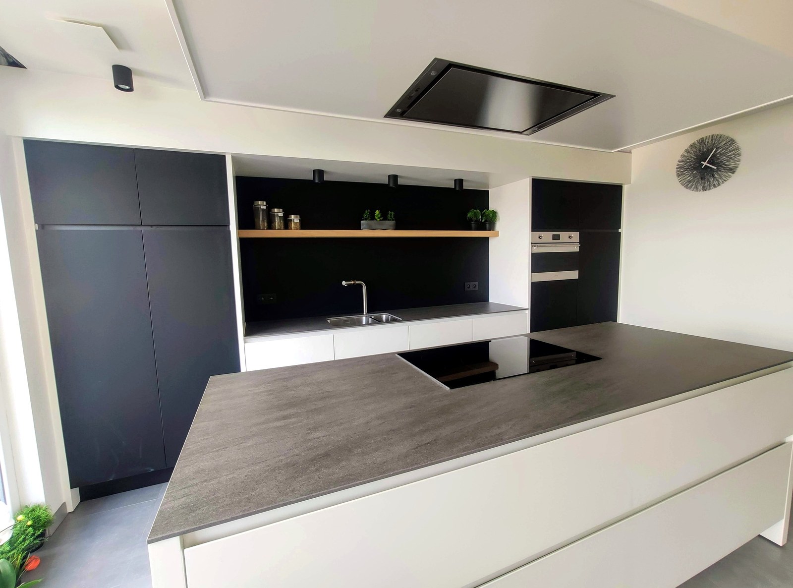 Moderne keuken op maat met zwarte fronten en grijze werkblad, professionele renovatie uitgevoerd in Oost-Vlaanderen door T Nieuw Project.