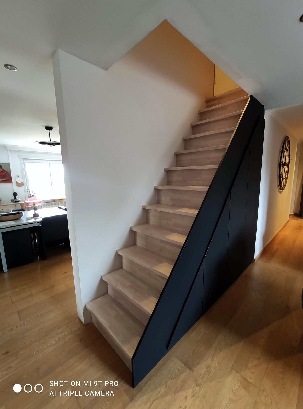 Moderne trap op maat met zwarte zijwand en houten treden in gerenoveerd interieur Oost-Vlaanderen, professionele renovatie en afwerking