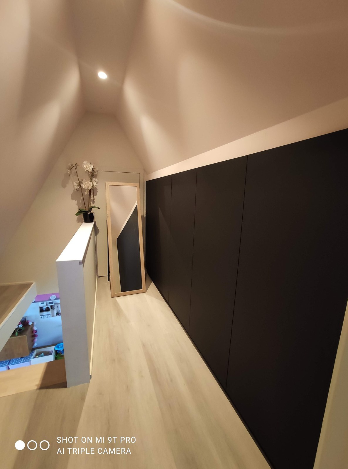 Moderne hallway renovatie met zwarte inbouwkasten op maat en stucwerk afwerking in Oost-Vlaanderen
