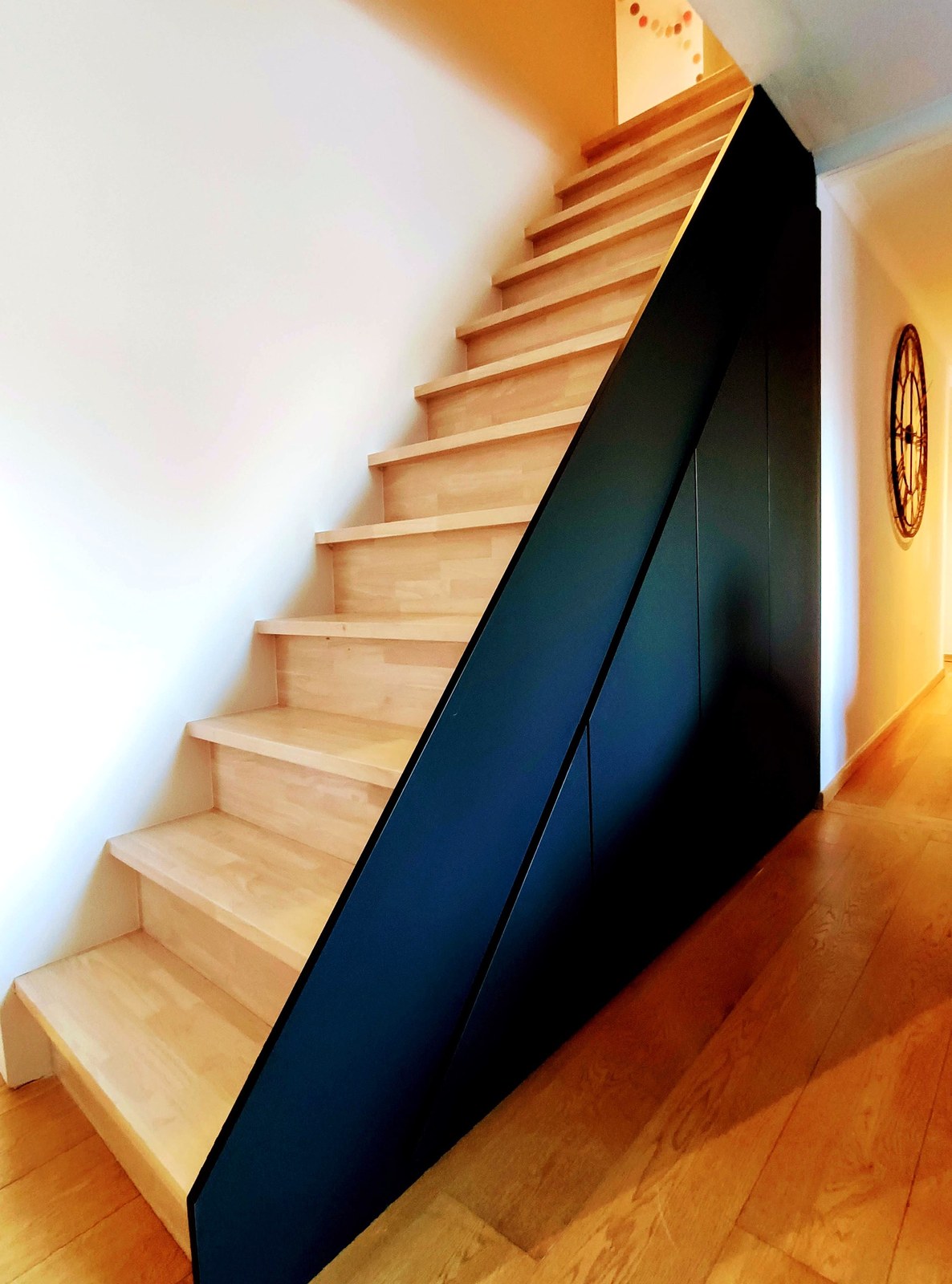 Moderne trap met zwarte op maat gemaakte wangstuk en houten treden, professionele renovatie uitgevoerd in Oost-Vlaanderen.