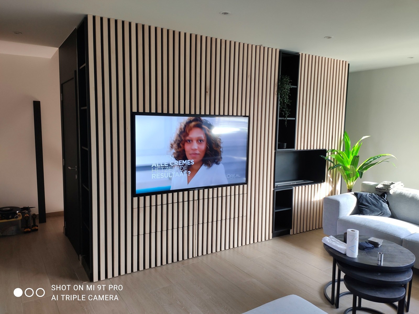 Modern TV-meubel op maat met houten latten design. Renovatie interieur Oost-Vlaanderen met maatwerk afwerking en minimalistisch ontwerp.