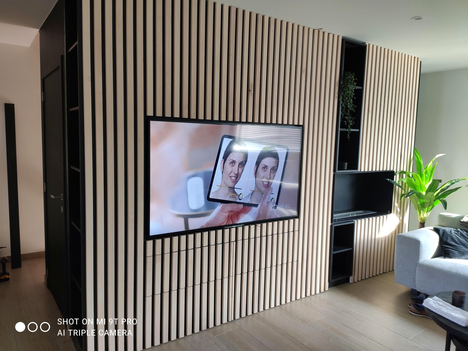 Moderne interieurwand op maat met houten latten en ingebouwde TV, professionele renovatie in Oost-Vlaanderen door T Nieuw Project