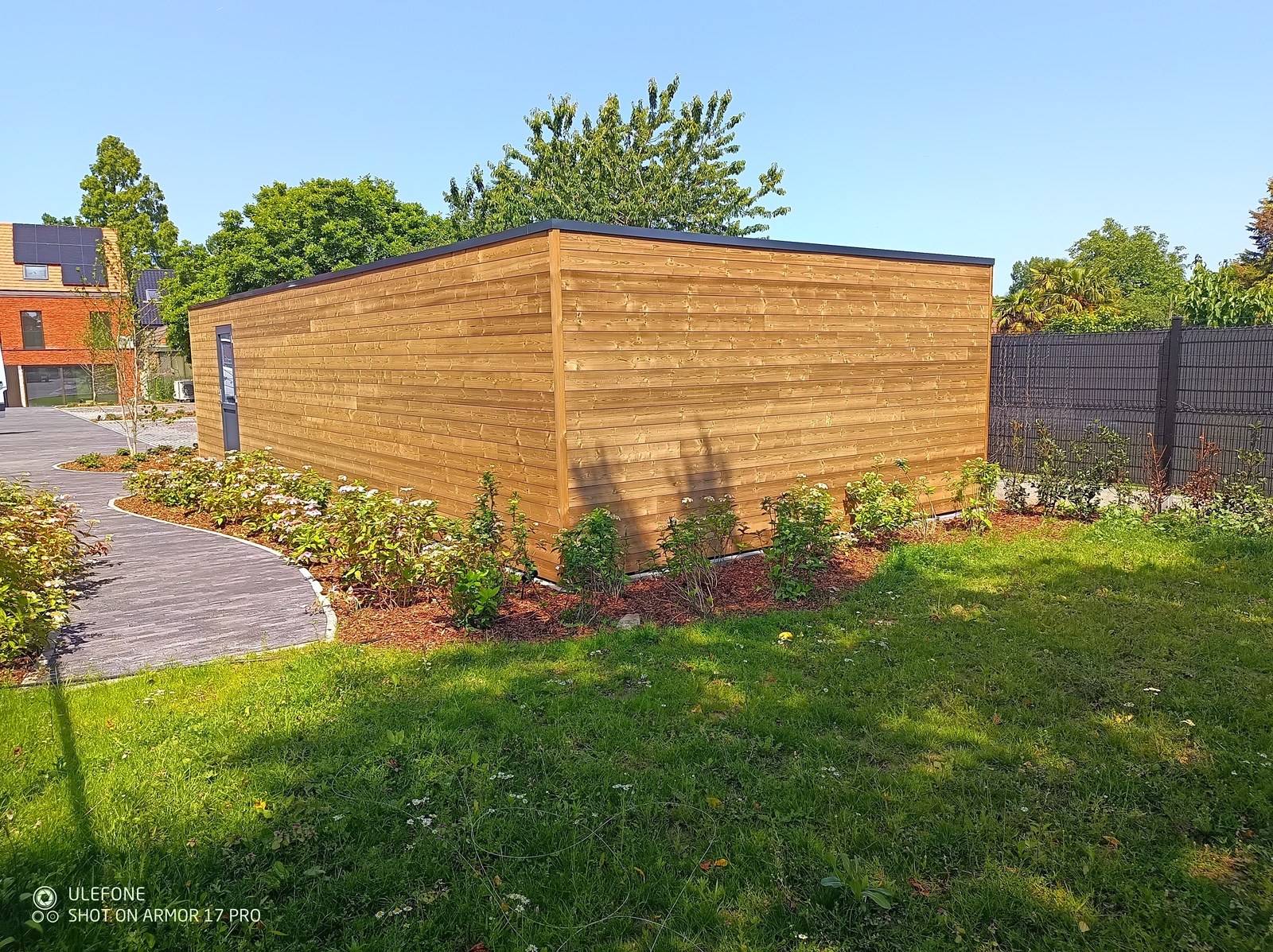 Moderne houten tuinschuur op maat gebouwd, perfect geïntegreerd in aangelegde tuin tijdens renovatieproject in Oost-Vlaanderen.