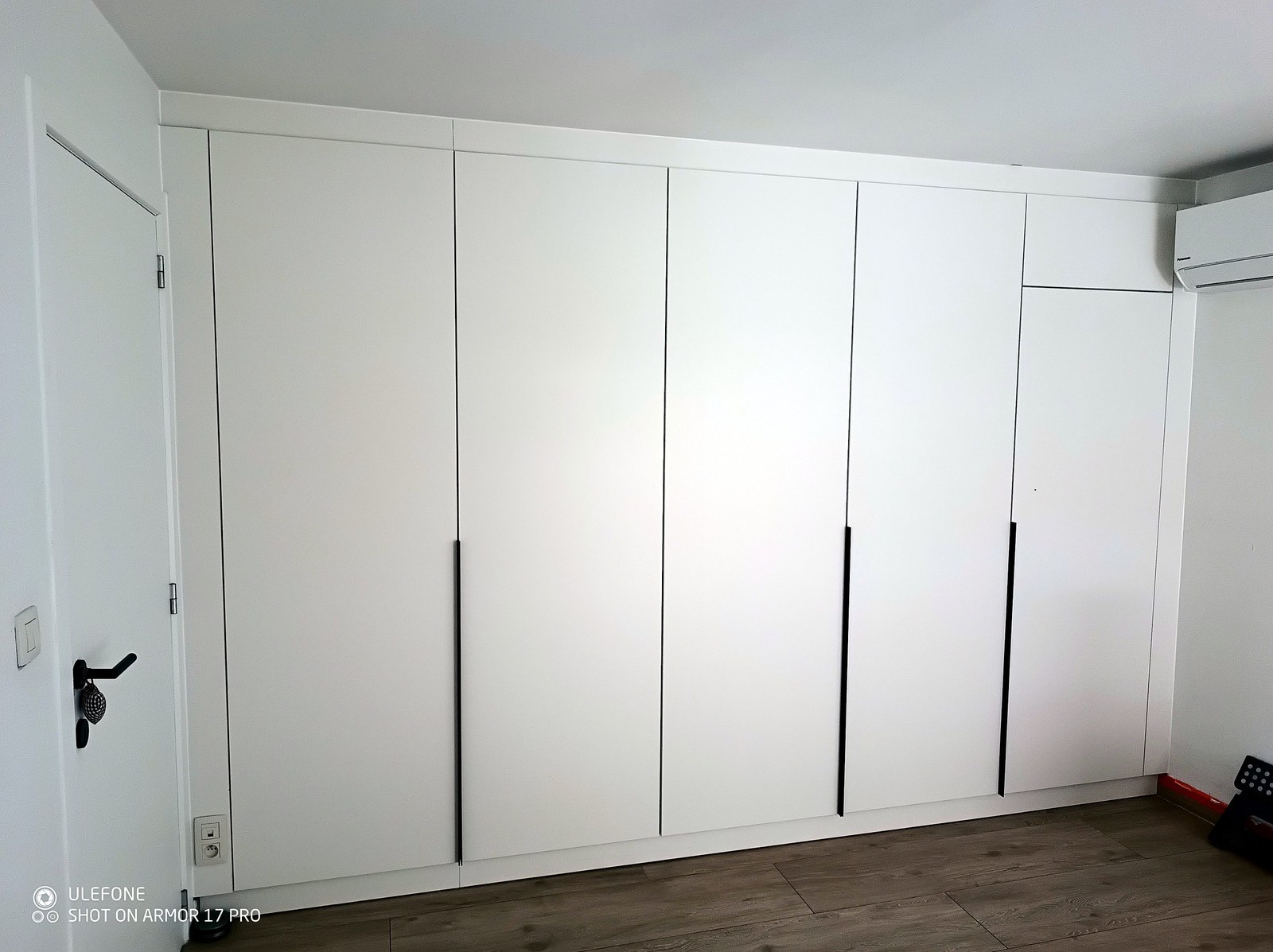 Moderne witte garderobekast op maat met zwarte hengsels, professionele renovatie en maatwerk interieur in Oost-Vlaanderen.